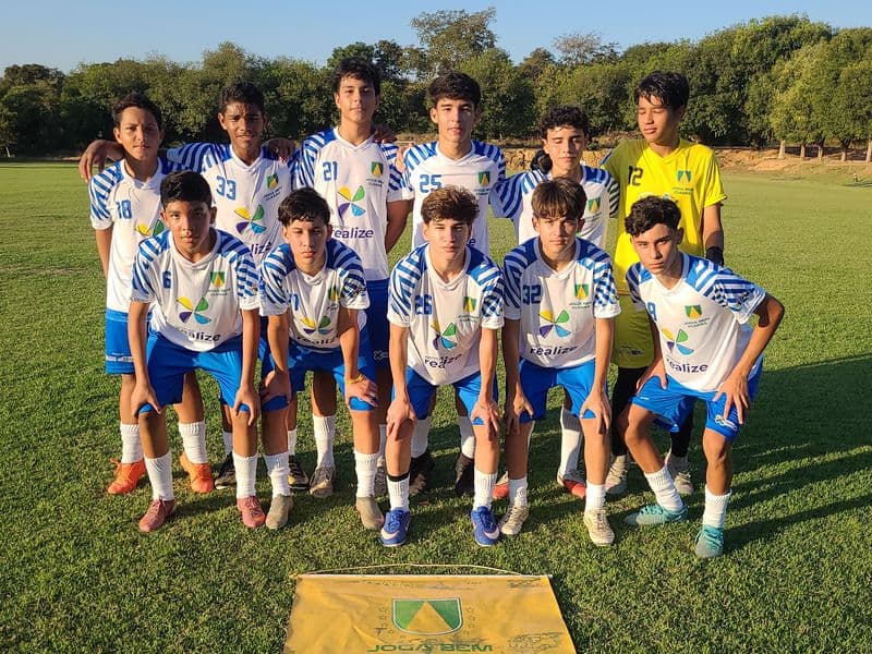 foto com alunos do projeto uniformizados em formação clássica em um campo de futebol gramado